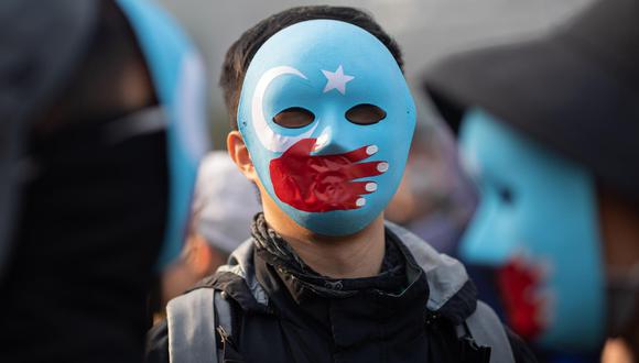 Un manifestante luce una máscara con los colores de la bandera de la Primera República del Turkestán Oriental y una mano de color rojo que representa a China. (Foto: Jerome Favre / Archivo EFE)