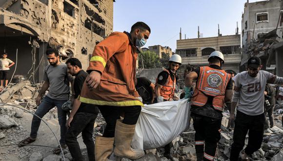 Miembros de la defensa civil palestina llevan el cuerpo de una víctima que murió durante el bombardeo israelí después de ser rescatada de los escombros de un edificio destruido en Khan Yunis, en el sur de la Franja de Gaza, el 25 de octubre de 2023, en medio de las batallas en curso entre Israel y los palestinos. grupo Hamás. (Foto de Mahmud HAMS / AFP)