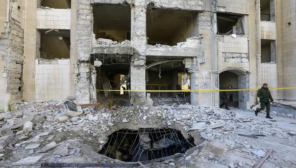 Miembros de las fuerzas de seguridad sirias inspeccionan un edificio dañado en un ataque con misiles israelí en Damasco el 19 de febrero de 2023. (Foto de Louai BESHARA / AFP)