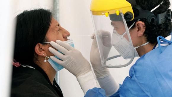 En la imagen, una trabajadora de la salud toma una muestra nasal de COVID-19 de una mujer para una prueba de PCR. (Foto de archivo: Cristina Vega/ RHOR/AFP)