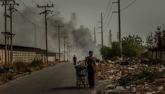 En Maracaibo, dos hombres revisaban los desperdicios en busca de objetos que todavía sirvieran o que pudieran ser reciclados. (Meridith Kohut para The New York Times).