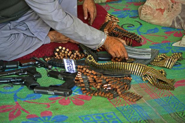 An Afghan vendor displays weapons for sale as he waits for customers at his shop in a market in the Panjwai district.