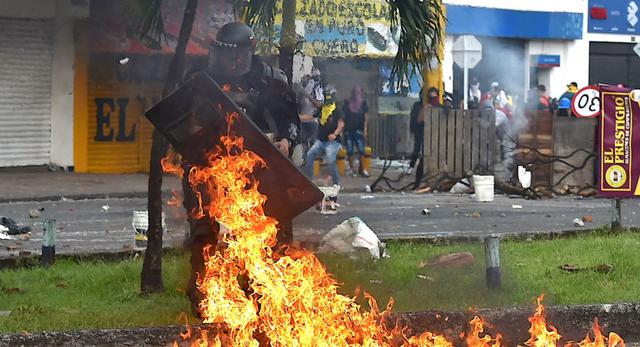 Un oficial de la policía antidisturbios lo atrapó con un cóctel molotov arrojado durante los enfrentamientos con manifestantes que protestaban contra un proyecto de ley de reforma tributaria lanzado por el presidente Iván Duque, a pesar de que el presidente ordenó entonces que la propuesta fuera retirada del Congreso, en Cali, Colombia. (Foto: AFP / Luis ROBAYO).