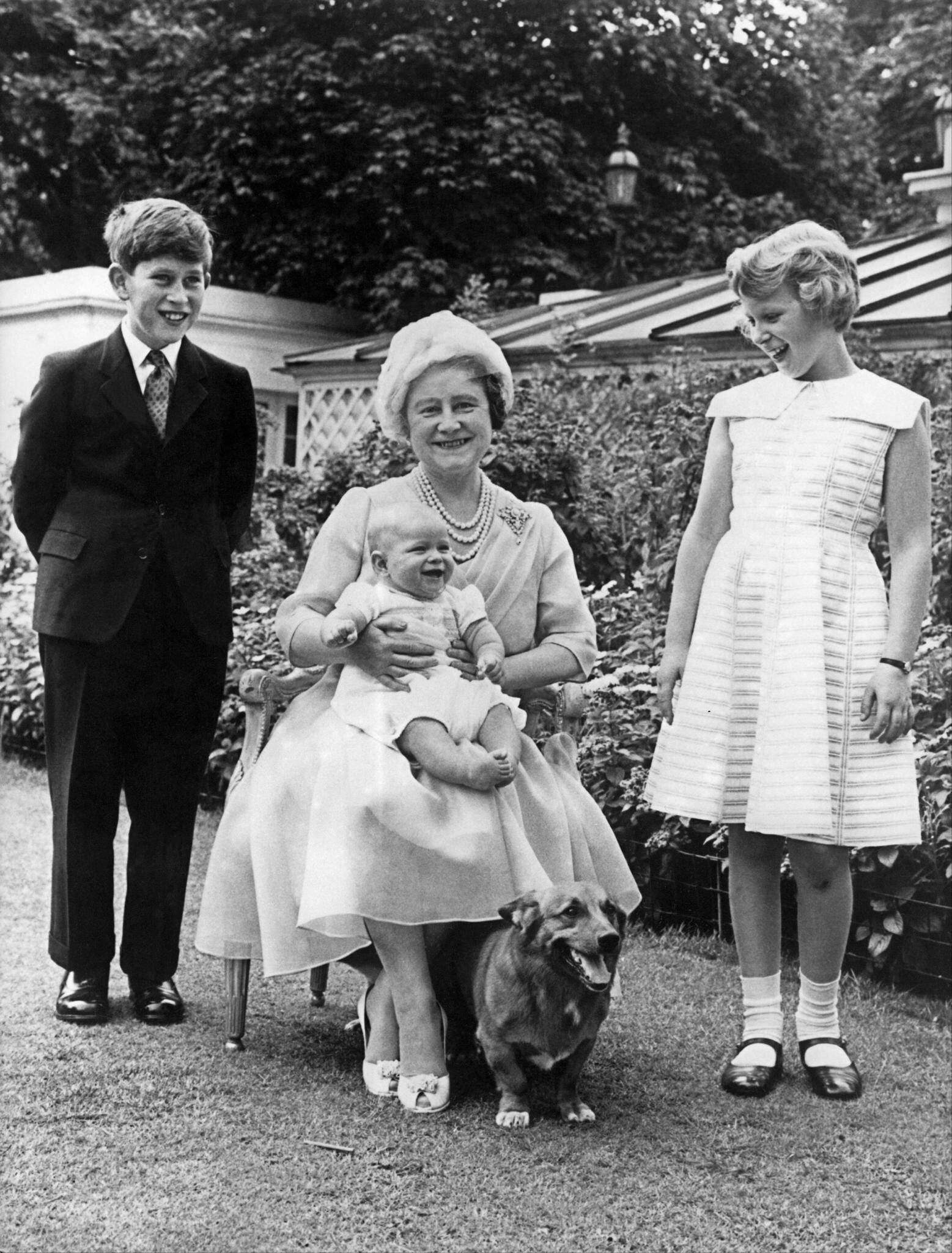 La reina Isabel, -madre de la actual monarca- sostiene al príncipe Andrés en su regazo y aparece flanqueada del príncipe Carlos y la princesa Ana durante su cumpleaños 60, celebrado el 4 de agosto de 1960 en el jardín de la residencia real Clarence House. (AFP)