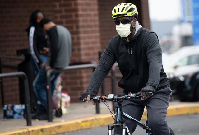 Un hombre, con una máscara para tratar de prevenir la propagación de COVID-19, conocido como coronavirus, llega en bicicleta a un supermercado en Estados Unidos. (Foto: AFP/Saul Loeb)
