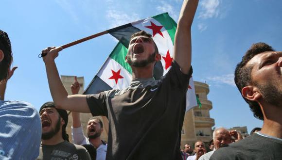 Manifestantes sirios agitan la bandera de la oposición mientras protestan contra el régimen y su aliado Rusia, en la ciudad de Idlib, controlada por los rebeldes. (Foto: AFP)