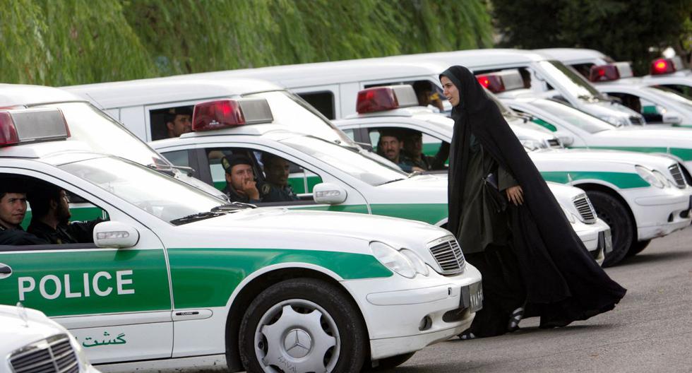 En esta foto de archivo tomada el 23 de julio de 2007, una mujer camina entre vehículos de la policía de Irán que se prepara para iniciar un operativo para hacer cumplir el código de vestimenta islámico en la capital, Teherán. (BEHROUZ MEHRI / AFP).