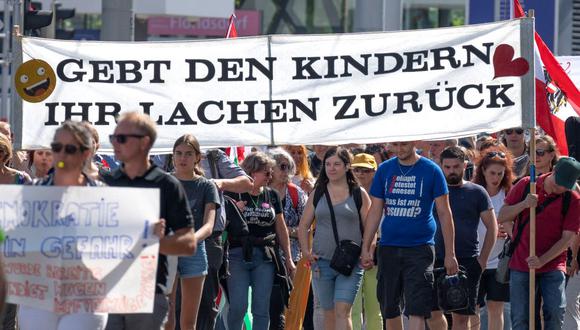 En esta foto del 11 de septiembre de 2021, los manifestantes sostienen una pancarta que dice "Devuélvales la sonrisa a los niños" durante una protesta contra las medidas del Gobierno de Austria  relacionadas con la pandemia del coronavirus. (JOE KLAMAR / AFP).