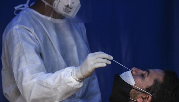 Un trabajador de la salud toma una muestra de un hisopo de un hombre para una prueba de coronavirus en Bogotá (Colombia), el 10 de abril de 2021. (Juan BARRETO / AFP).