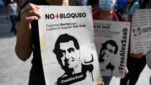 La gente sostiene carteles con la imagen del empresario colombiano Álex Saab, quien está detenido en Estados Unidos, durante una manifestación en Caracas para exigir su liberación, el 17 de octubre de 2021. (Federico PARRA / AFP).