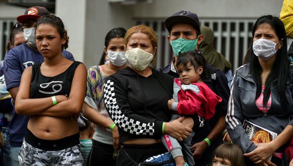 Migrantes venezolanos esperan para abordar un autobús para regresar voluntariamente a su país debido a la pandemia de coronavirus COVID-19, en Cali, Colombia. (AFP / Luis ROBAYO).