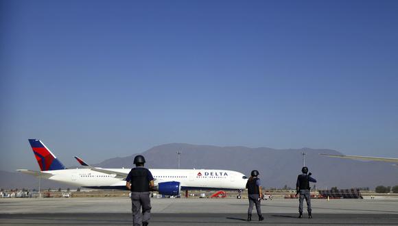 Agentes de policía caminan cerca de un avión de Delta Air Lines en la pista del Aeropuerto Internacional Arturo Merino Benítez en Santiago el 8 de marzo de 2023. (Foto de Karin POZO / AFP)