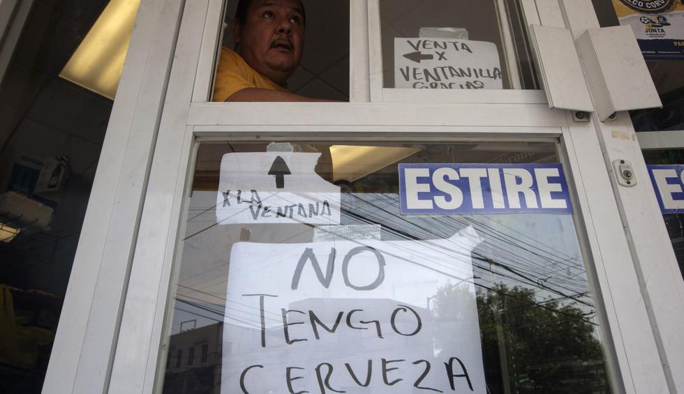 Un hombre en una tienda de cerveza está parado detrás de un cartel que dice "No tengo cerveza" en Monterrey, estado de Nuevo León, México. (Julio César AGUILAR / AFP).