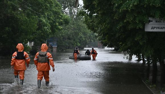Rescatistas del Servicio Estatal de Emergencias ayudan a evacuar a un residente local de un área inundada en la ciudad de Kherson el 11 de junio de 2023. (Foto de Genya SAVILOV / AFP)