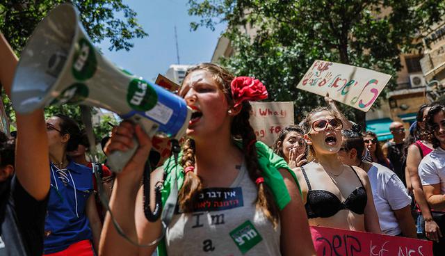 Israeli activists chant slogans, as they carry placards, during the 6th annual SlutWalk march through central Jerusalem on June 2, 2017, to protest rape culture, including the sexual assault and harassment of women The campaign, which has gained international notoriety, was inspired by group of Canadian women who launched the protest in 2011 in response to a policeman's comment that if women want to avoid being attacked they should not dress like sluts. / AFP / GALI TIBBON