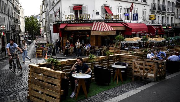 La gente toma unas copas en la terraza ampliada de un café en París el 23 de julio de 2020, en medio de la pandemia del coronavirus COVID-19. (Foto de Christophe ARCHAMBAULT / AFP).