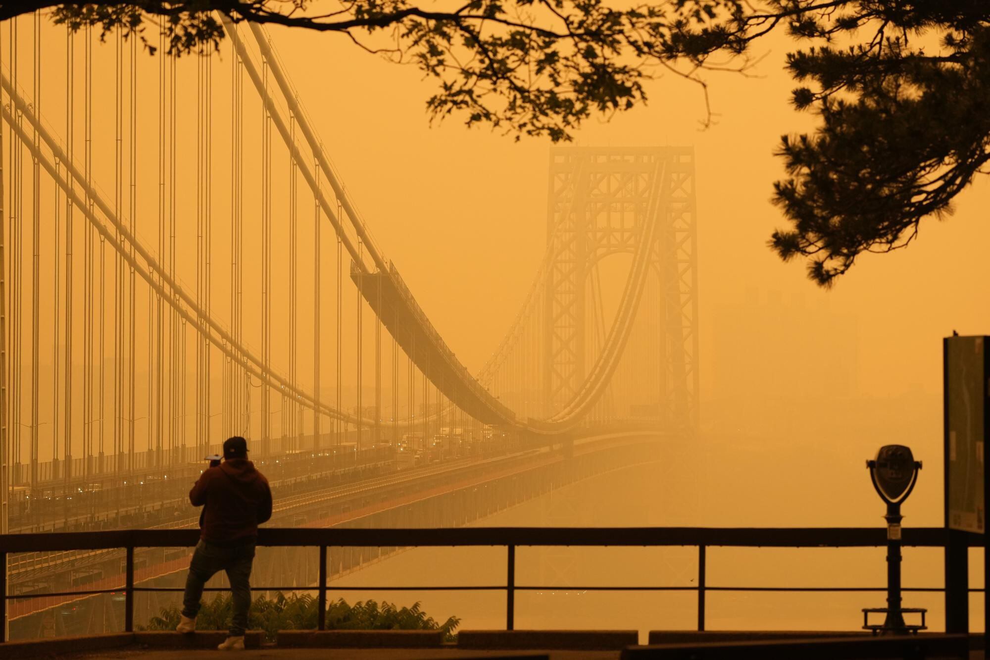 A man talks on the phone as he looks through fog at the George Washington Bridge, Wednesday, June 7, 2023. (AP Photo/Seth Wenig)