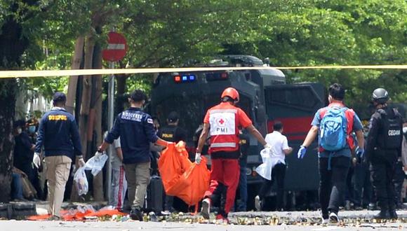 Policías forenses llevan una bolsa para cadáveres frente a la Catedral del Sagrado Corazón de Jesús tras una explosión, en Makassar, Indonesia,el  28 de marzo de 2021. (EFE / EPA / IQBAL LUBIS).