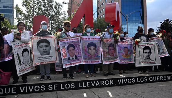 La gente lleva carteles de los estudiantes desaparecidos durante una marcha en la Ciudad de México. (Foto de Rodrigo ARANGUA / AFP)