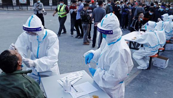 Un trabajador médico con traje protector recoge un hisopo de un residente en un sitio de prueba de ácido nucleico improvisado, luego de casos de la enfermedad por coronavirus (COVID-19) en Shanghái, China. (Foto: cnsphoto vía REUTERS).