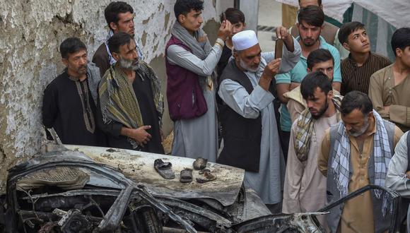 Residentes afganos y familiares de las víctimas se reúnen junto a un vehículo dañado dentro de una casa, un día después de un ataque aéreo con aviones no tripulados estadounidenses en Kabul, Afganistán, el 30 de agosto de 2021. (WAKIL KOHSAR / AFP).