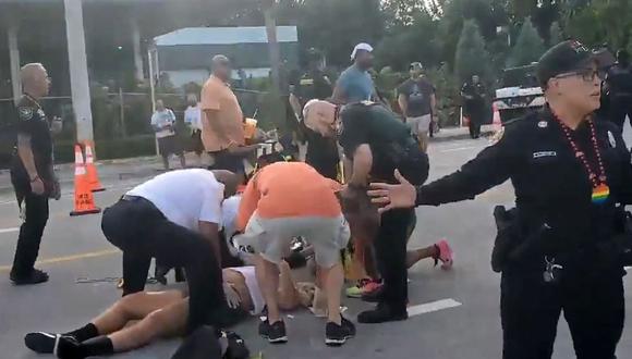 Oficiales de policía y otras personas ayudan a dos personas que yacen en el suelo después de ser atropelladas por una camioneta durante un desfile del Orgullo LGTBQ en Wilton Manors, cerca de Fort Lauderdale, Florida. (AFP).