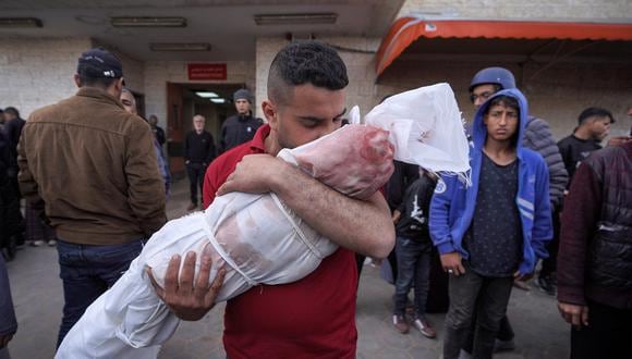 Un palestino besa el cuerpo envuelto de un niño muerto en un bombardeo israelí en Deir el-Balah, en el centro de la Franja de Gaza, antes del entierro el 14 de marzo de 2024. (Foto de AFP)