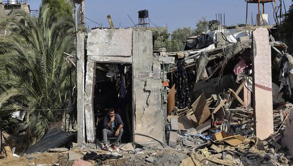 Palestinos inspeccionan sus pertenencias entre los escombros de su casa en el campo de refugiados de Nusseirat en Gaza, el 14 de mayo de 2023. (Foto de Mohammed ABED / AFP)