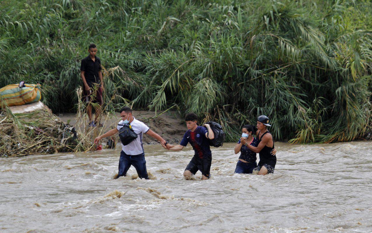 Ciudadanos venezolanos cruzan el fuerte caudal del río Táchira, este jueves, en la ciudad de Cúcuta en un intento por llegar a Colombia. (Foto: SCHNEYDER MENDOZA / AFP)