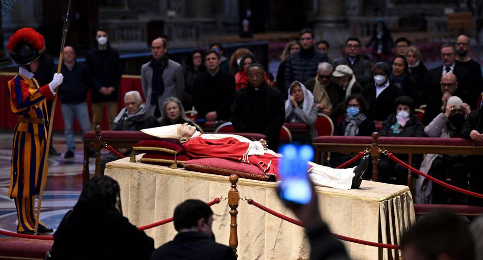 La gente toma fotografías del papa emérito Benedicto XVI mientras su cuerpo yace en la Basílica de San Pedro en el Vaticano, el 2 de enero de 2023. (ANDREAS SOLARO / AFP).