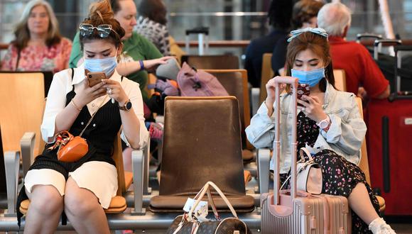 Los viajeros que usan máscaras protectoras en medio de los temores sobre la propagación del nuevo coronavirus COVID-19, esperan en la sala de embarque del Aeropuerto Internacional de Changi, en Singapur. (AFP / Roslan RAHMAN).