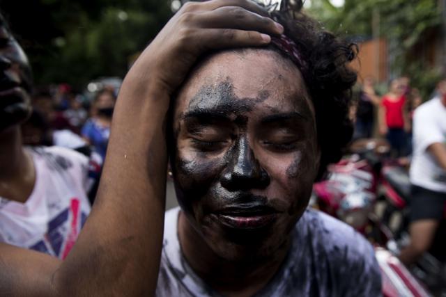 Un "promesante" se llena el cuerpo con aceite negro a modo de penitencia para cumplir con la tradición de "Los Diablitos Negros" durante una procesión en honor a Santo Domingo de Guzmán en Managua (Nicaragua). (EFE/ Jorge Torres).