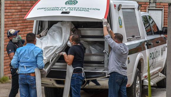 Policías descargan los cadáveres de víctimas de una masacre presuntamente a manos de grupos armados en el municipio colombiano de Arauca. (Foto Referencial: AFP/Daniel Fernando Martinez/Archivo).