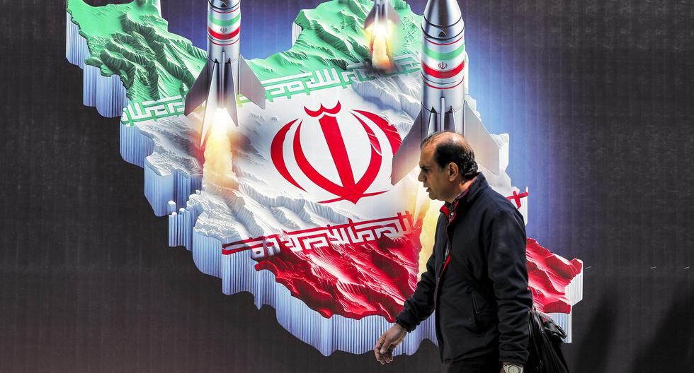 Un hombre pasa junto a una pancarta que representa misiles lanzados desde una representación del mapa de Irán centro de Teherán el 15 de abril de 2024. (Foto de ATTA KENARE / AFP).