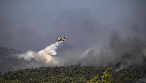 Un avión de extinción de incendios de Canadair rocía agua durante un incendio en Dervenochoria, al noroeste de Atenas. (Foto de Spyros BAKALIS / AFP)