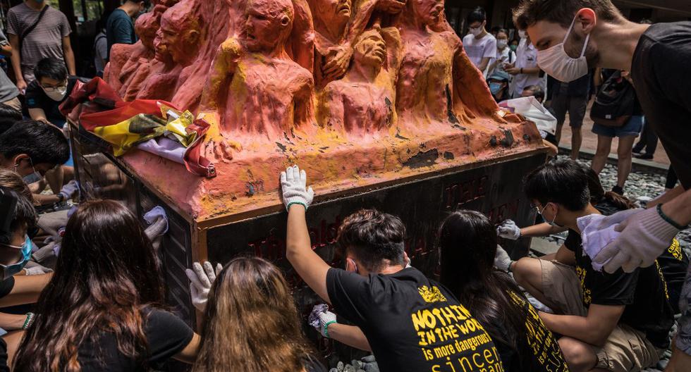 Estudiantes universitarios limpian el Pilar de la Vergüenza, una estatua del artista danés Jens Galschiot para recordar a las víctimas de la represión de Tiananmen, en la Universidad de Hong Kong. (DALE DE LA REY / AFP)