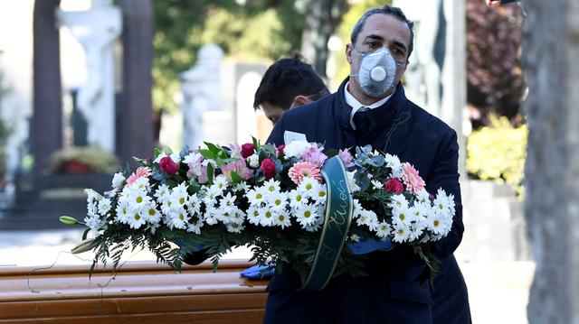 Trabajadores de un cementerio y de una agencia funeraria transportan un ataúd que contien los restos de una persona que murió por coronavirus en Bérgamo, Italia. (REUTERS / Flavio Lo Scalzo / File Photo).