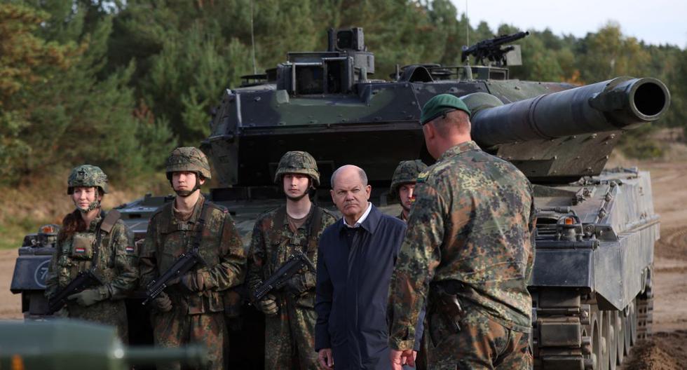 El canciller alemán Olaf Scholz (centro) escucha frente a un tanque de batalla principal Leopard 2. (Ronny HARTMANN / AFP).