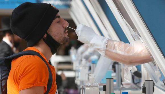 n médico recolecta una muestra de hisopo de un viajero en un stand en el centro de pruebas rápidas de coronavirus COVID-19 en el Aeropuerto Internacional Ben Gurion de Israel. (Foto: AFP / JACK GUEZ).