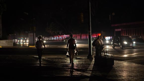 Imagen de archivo | La gente camina por una calle oscura durante un nuevo apagón en Caracas. (Foto por CRISTIAN HERNÁNDEZ / AFP)
