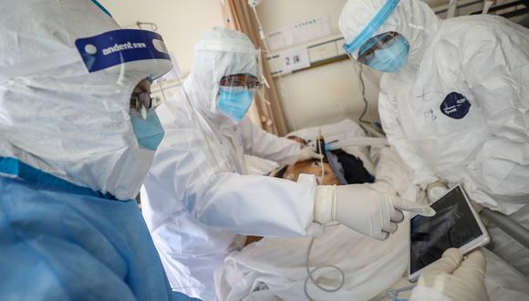 Esta foto tomada el 16 de febrero de 2020 muestra a un equipo médico revisando a un paciente de coronavirus en el Hospital de la Cruz Roja de Wuhan en Wuhan, en China. Foto: AFP