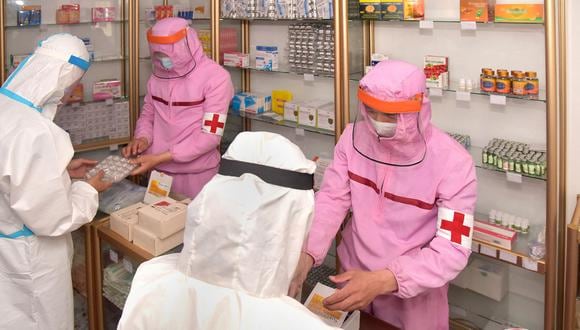 Personal médico del Ejército Popular de Corea con ropa protectora que suministra medicamentos en una farmacia en Pyongyang, el 31 de mayo de 2022. (Foto referencial de KCNA VIA KNS / AFP)