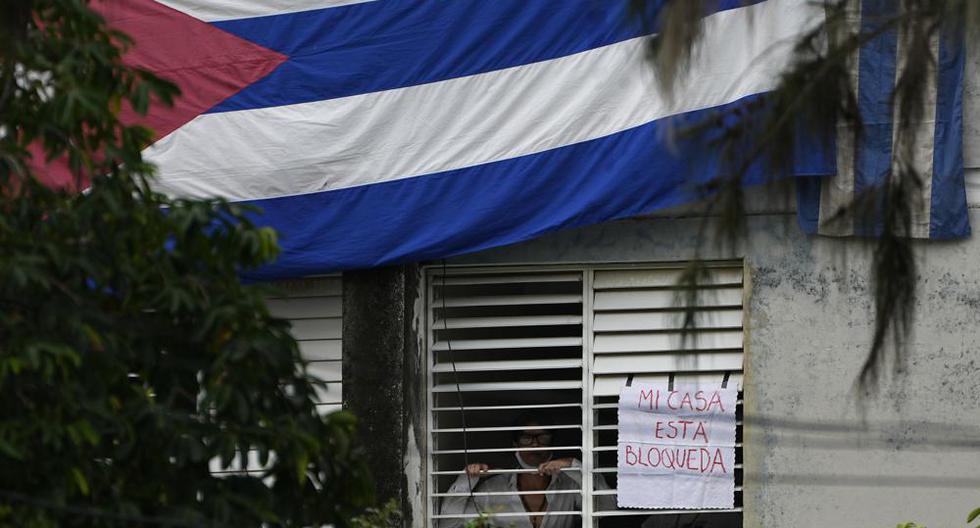 Yunior García Aguilera, dramaturgo y uno de los organizadores de una marcha de protesta el 15 de noviembre, aparece junto a un letrero que dice "Mi casa está bloqueada", que colgó en una ventana de su domicilio en La Habana, Cuba, el domingo 14 de noviembre de 2021. (Foto AP/Ramón Epinosa).