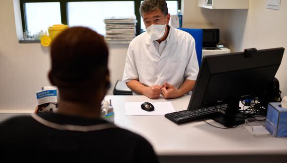 Un médico conversa con un hombre antes de recibir una dosis de la vacuna contra la viruela del mono en París el 3 de agosto de 2022. (Foto referencial: JULIEN DE ROSA / AFP)