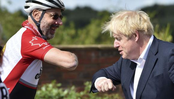 El primer ministro británico, Boris Johnson, se saluda con el codo con el ciclista Robert Cleave el 28 de julio de 2020, en plena pandemia de coronavirus. (Foto de Rui Vieira / POOL / AFP).