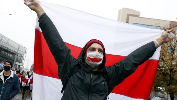Un hombre porta una antigua bandera blanca-roja-blanca de Bielorrusia durante un mitin para protestar contra los resultados de las elecciones presidenciales que dieron como ganador a Alexander Lukashenko. (Foto: AFP).