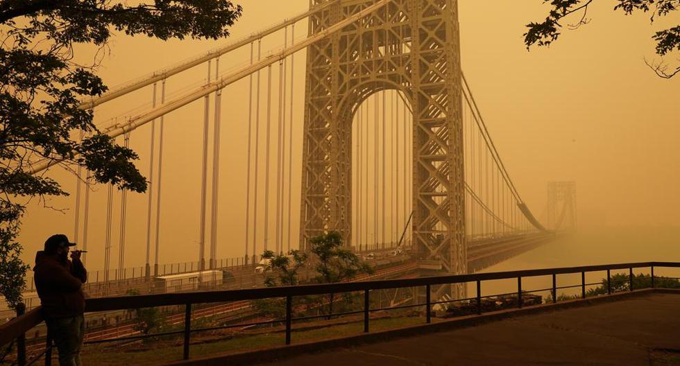 Un hombre habla por teléfono mientras mira a través del humo en el puente George Washington en Fort Lee, Nueva Jersey, el miércoles 7 de junio de 2023. (Foto AP/Seth Wenig).