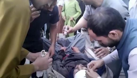 En esta toma de fotograma del video, las personas atienden a un hombre herido cerca del lugar de una explosión mortal afuera del aeropuerto en Kabul, Afganistán, el jueves 26 de agosto de 2021. (Foto AP).