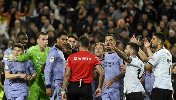 Spanish referee Jesus Gil Manzano (back) talks with Real Madrid's English midfielder #5 Jude Bellingham (C,L) during the Spanish league football match between Valencia CF and Real Madrid at the Mestalla stadium in Valencia on March 2, 2024 (Photo by JOSE JORDAN / AFP)