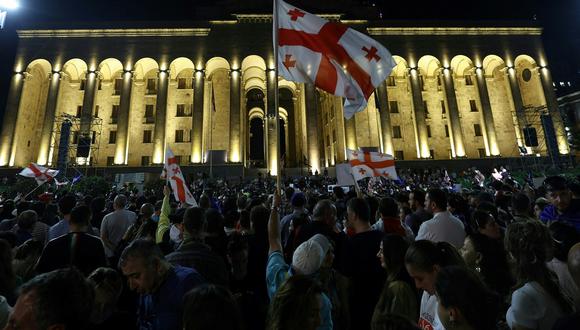 Manifestantes sostienen una bandera de Georgia mientras protestan frente al parlamento georgiano, en Tiflis, el 1 de mayo de 2024. (Foto de Giorgi ARJEVANIDZE / AFP)